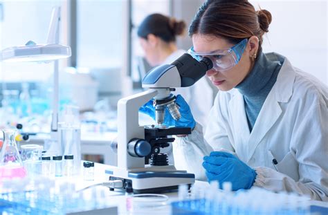 Scientist examining a sample under a microscope to identify and qualify pharmaceutical impurities